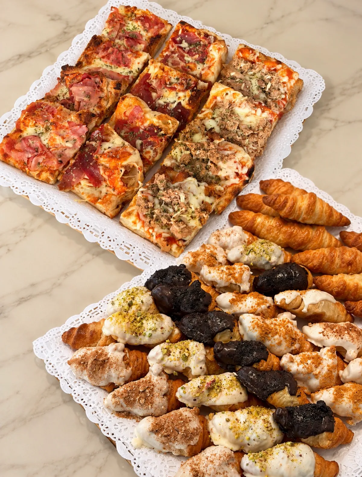 Dos bandejas de encargo: cuadrados de focaccia y mini croissants rellenos.