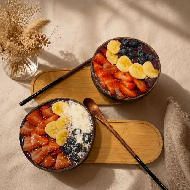 Dos açaí bowls con plátano, fresas y arándanos, vistos desde arriba.